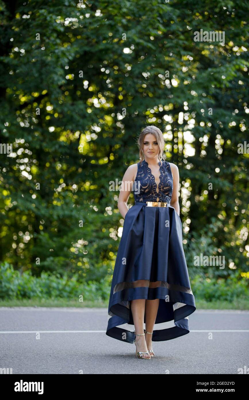 In der Mitte der Straße im Park steht eine junge Dame, die ein elegantes dunkelblaues  Kleid trägt Stockfotografie - Alamy