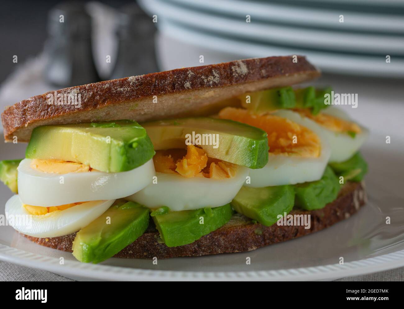 Gesundes Sandwich aus Sauerteig, Avocado und gekochten Eiern. Serviert auf einem Teller. Sehr Blick aus der Nähe Stockfoto