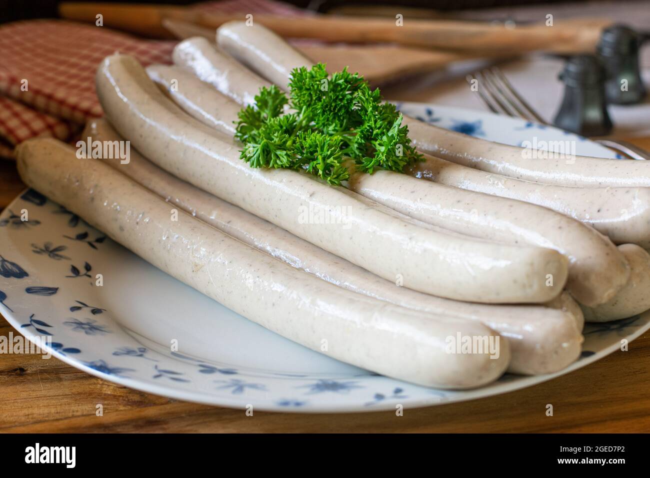 Traditionelle deutsche thüringer Bratwurst Thüringer Bratwurst. Roh auf einem rustikalen Teller auf einem Holztisch. Bereit zum Grillen Stockfoto