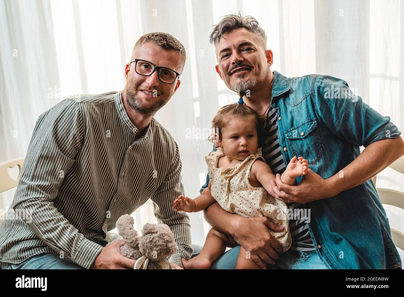 Porträt einer glücklichen LGBTQ-Familie zu Hause - Schwule Paare und ihre Tochter - Diversity-Konzept und LGBTQ-Familienbeziehung Stockfoto