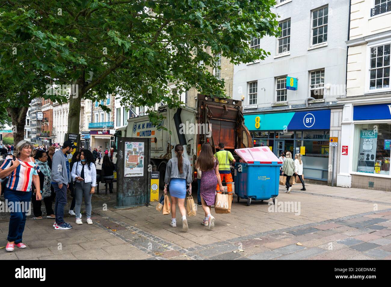 Mülleimer leert an einem geschäftigen Tag einen kommerziellen blauen Papierkorb im Zentrum von Norwich City Stockfoto