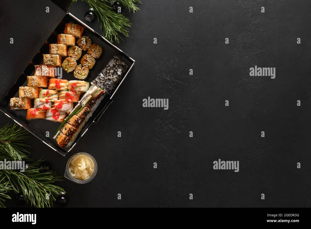 Speiselieferung für asiatisches Sushi-Set für Weihnachtsessen oder Neujahrsparty auf schwarzem Hintergrund. Blick von oben. Speicherplatz kopieren. Stockfoto