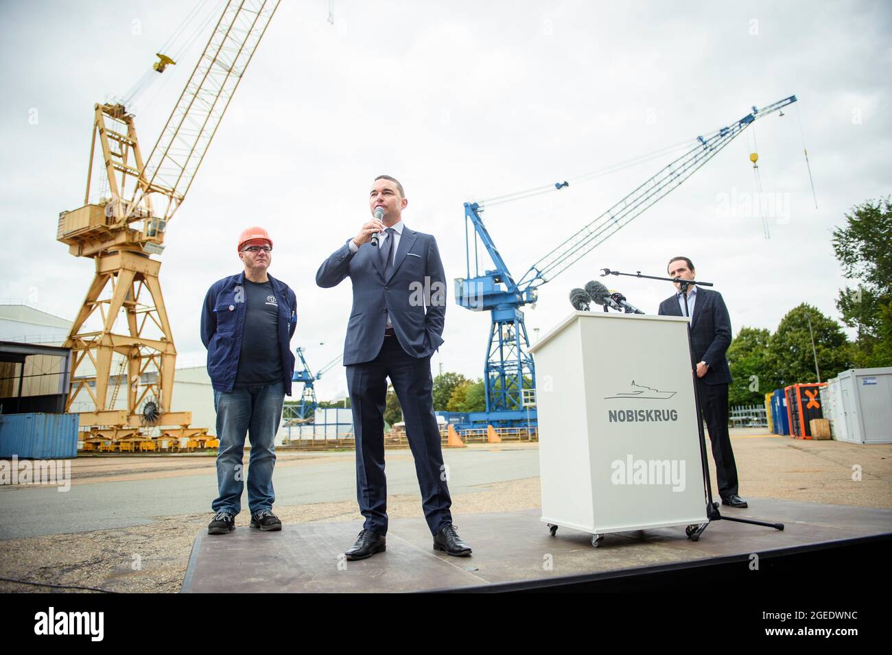 19. August 2021, Schleswig-Holstein, Rendsburg: Marcus Stöcken (l-r), Vorsitzender des Betriebsrats der Nobiskrug GmbH, Lars Windhorst, Unternehmer und Vorsitzender der Tennor Holding, Und Philipp Maracke, Geschäftsführer der Flensburger Schiffbau Gesellschaft mbH und der Nobiskrug GmbH, sprach im Rahmen einer Pressekonferenz nach der Übernahme der Nobiskrug-Werft durch die Flensburger Schiffbau Gesellschaft auf dem Nobiskrug-Werksgelände am Nord-Ostsee-Kanal mit Medienvertretern. Beide Schiffbauunternehmen sind Teil der Tennor Holding. Foto: Gregor Fischer/dpa Stockfoto