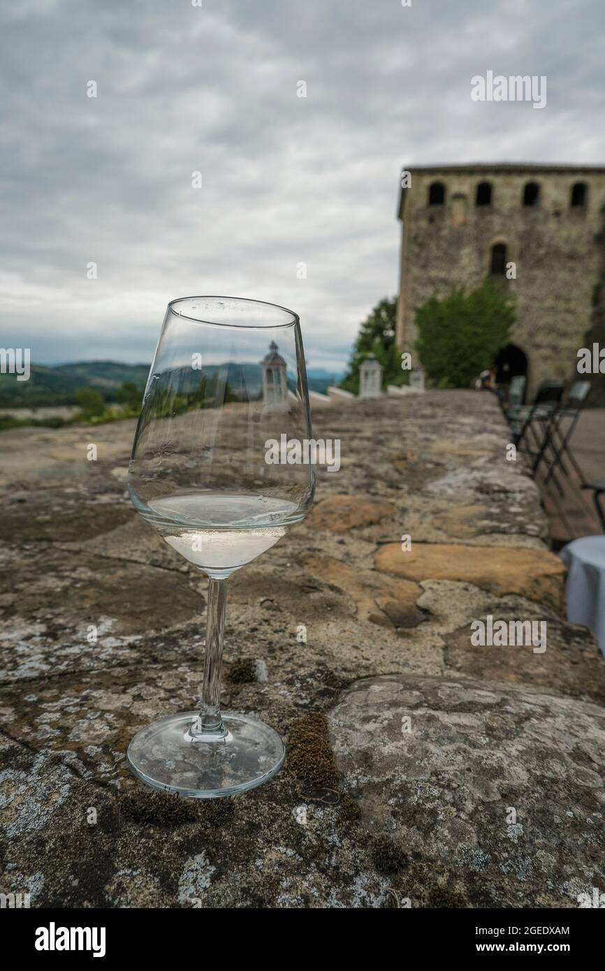Glas an der Wand des Schlosses. Glas Weißwein auf der Terrasse aus der Nähe über Schloss, Terrasse und blauen Himmel. Reisen, Weinindustrie Stockfoto