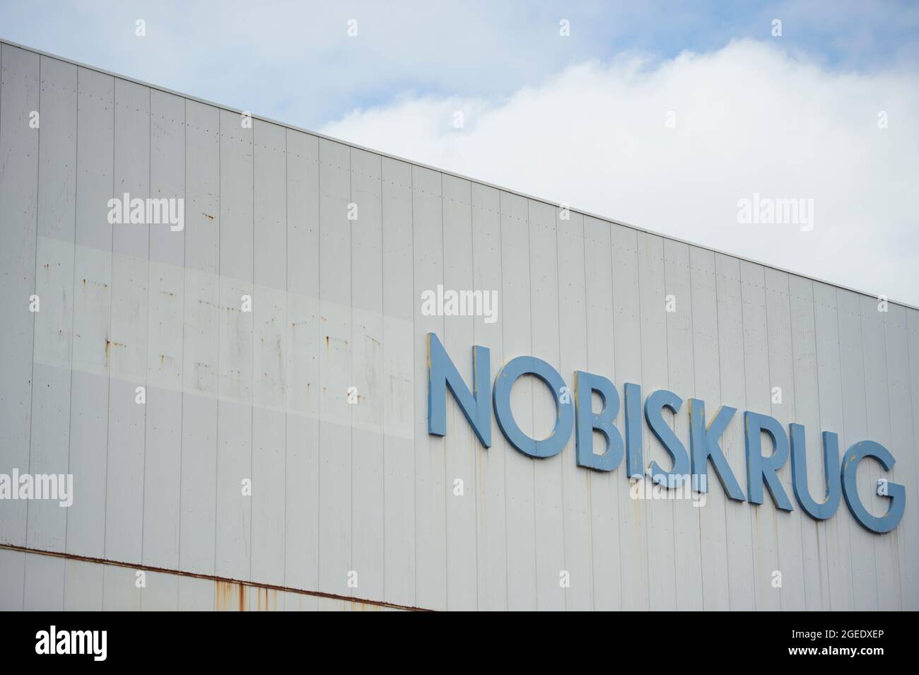Rendsburg, Deutschland. August 2021. Der Firmenname ('Nobiskrug') ist auf einer Fabrikhalle vom Fabriktor der Nobiskrug-Werft aus zu sehen. Die Werft am Nord-Ostsee-Kanal in Rendsburg wurde von der Flensburger Schiffbau-Gesellschaft übernommen. Quelle: Gregor Fischer/dpa/Alamy Live News Stockfoto