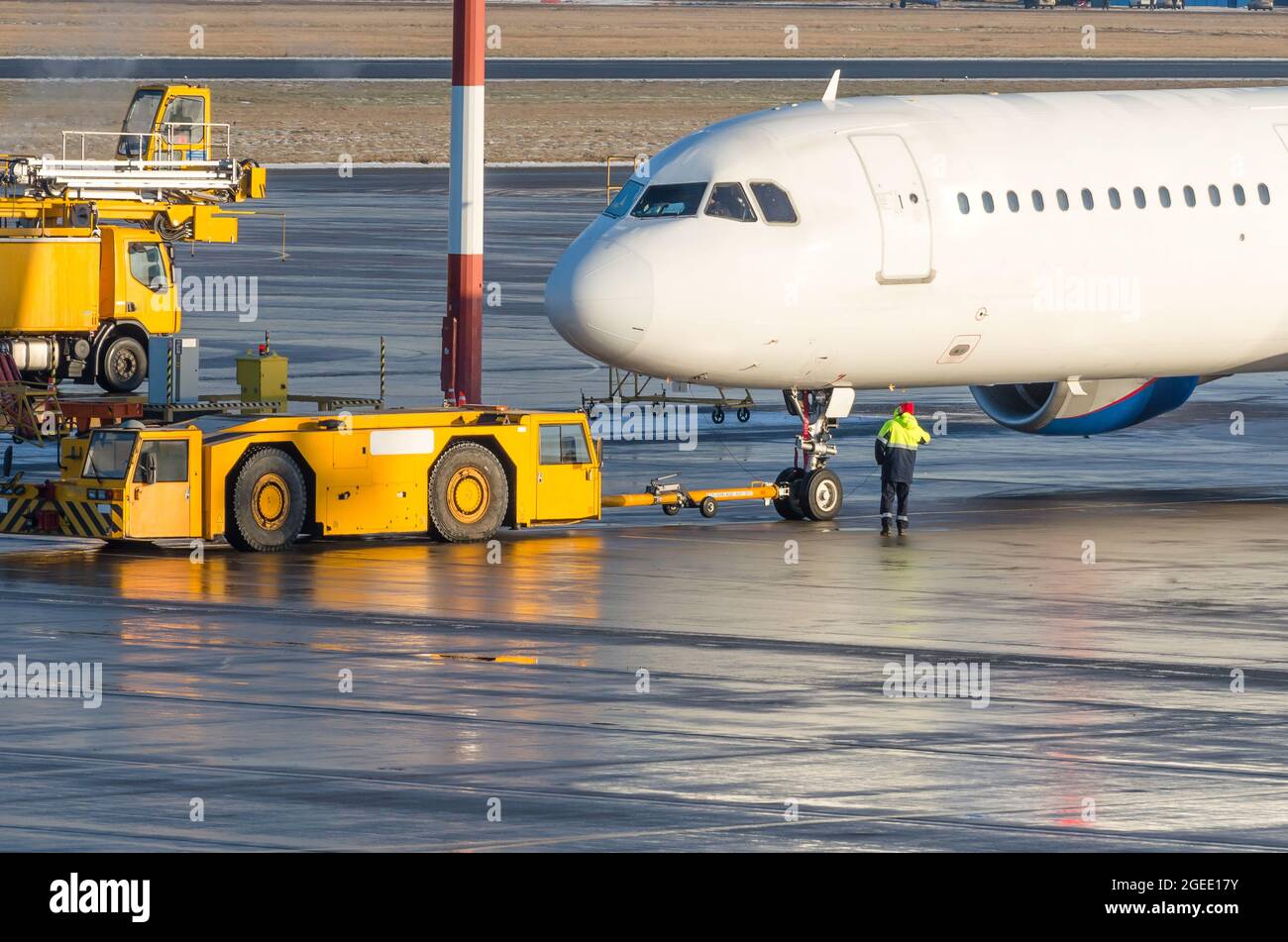 Der Rückzugschlepper schleppt das Flugzeug auf einen Parkplatz, Aviation marshall Stockfoto