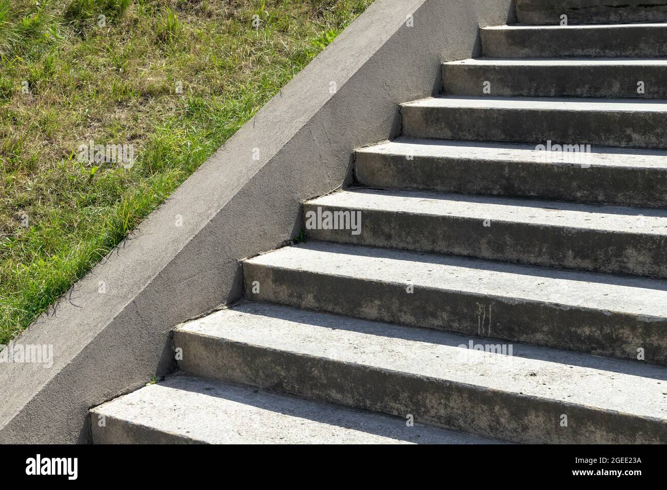 Abstrakter Architekturhintergrund mit einer leeren Betontreppe und grünem Gras an einem Hang Stockfoto