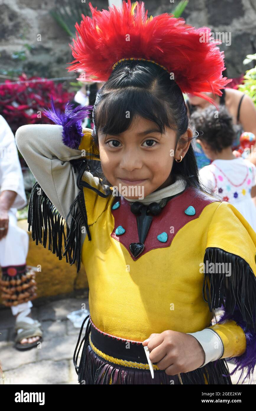 Eine junge aztekische Tänzerin posiert mit einem Lächeln, bevor sie sich dem Tanz anschließt. Stockfoto