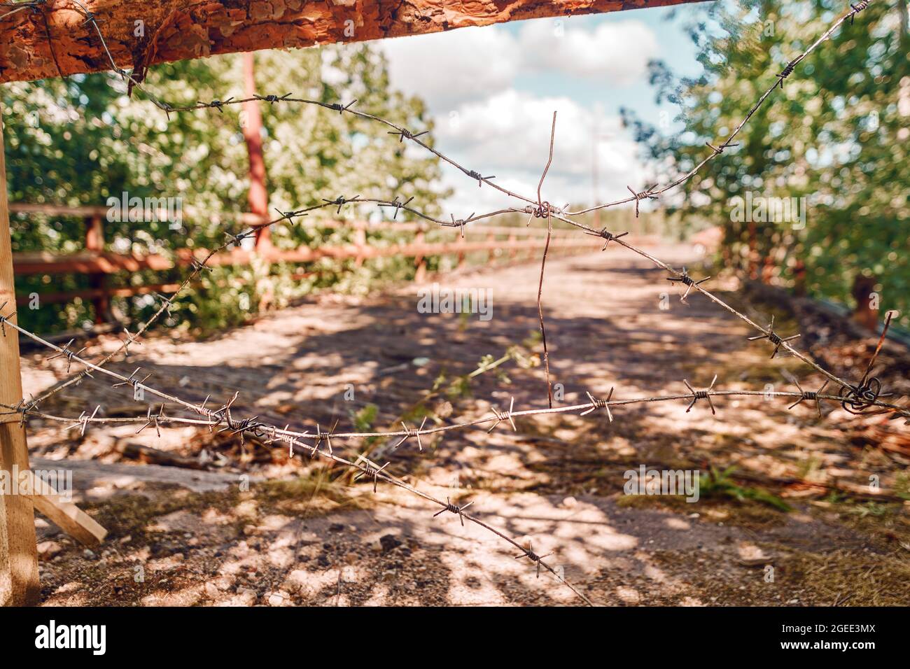 Rostiger Stacheldraht am Eingang zum verbotenen Bereich mit einer idyllischen, entkoksten Landschaft dahinter Stockfoto