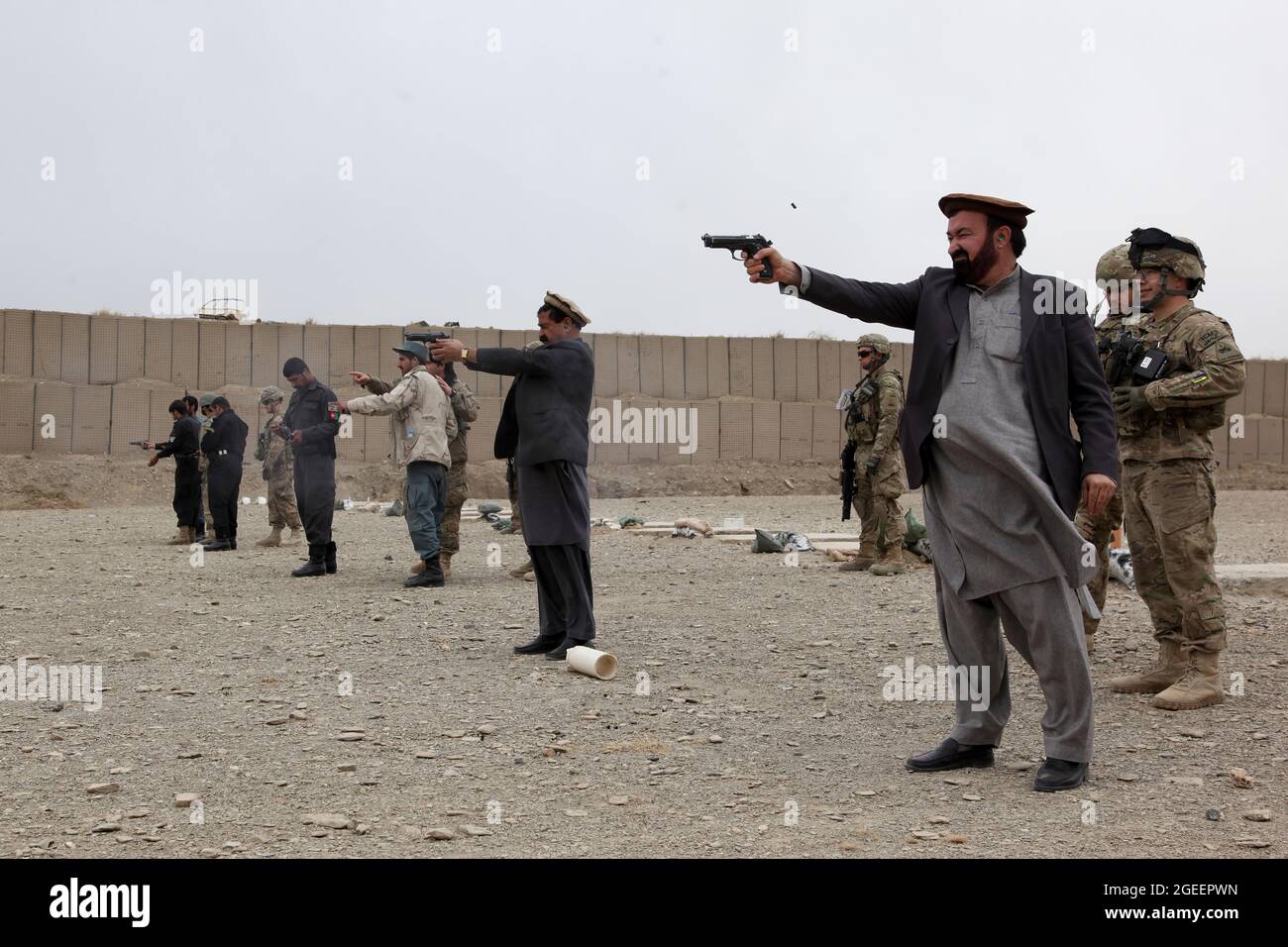 Mitarbeiter des afghanischen Nationalen Sicherheitsdirektorats und uniformierte afghanische Polizisten, die in der Stadt Khost stationiert sind, feuern M-9 Beretta-Pistolen auf einen kleinen Waffenbereich auf Camp Parsa, Provinz Khowst, Afghanistan, 30. Januar 2013. Soldaten der US-Armee, die dem Team 28 der Sicherheitskräfte, der Task Force 3/101, zugewiesen wurden, planten die Reichweite und unterstützten die AUP und die NDS beim sicheren Üben mit ihren Waffen. (USA Armeefoto von Sgt. Kimberly Trumbull / Veröffentlicht) Stockfoto
