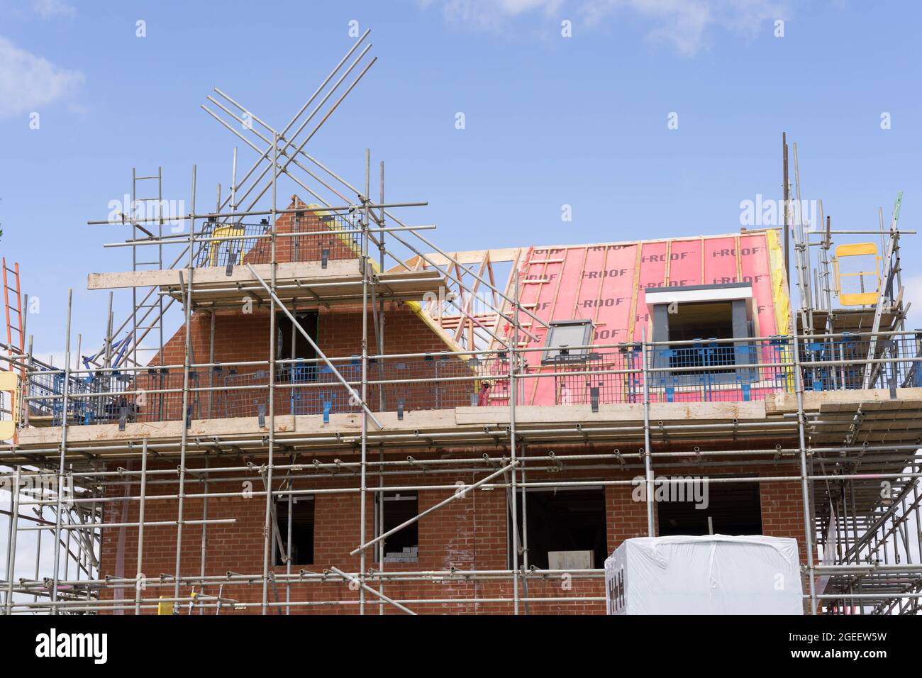 Neues Haus mit neuem Dach, das an sonnigen Sommertagen gebaut wird, blauer Himmel, Gerüste, rote Backsteinmauer, Buckinghamshire England Stockfoto