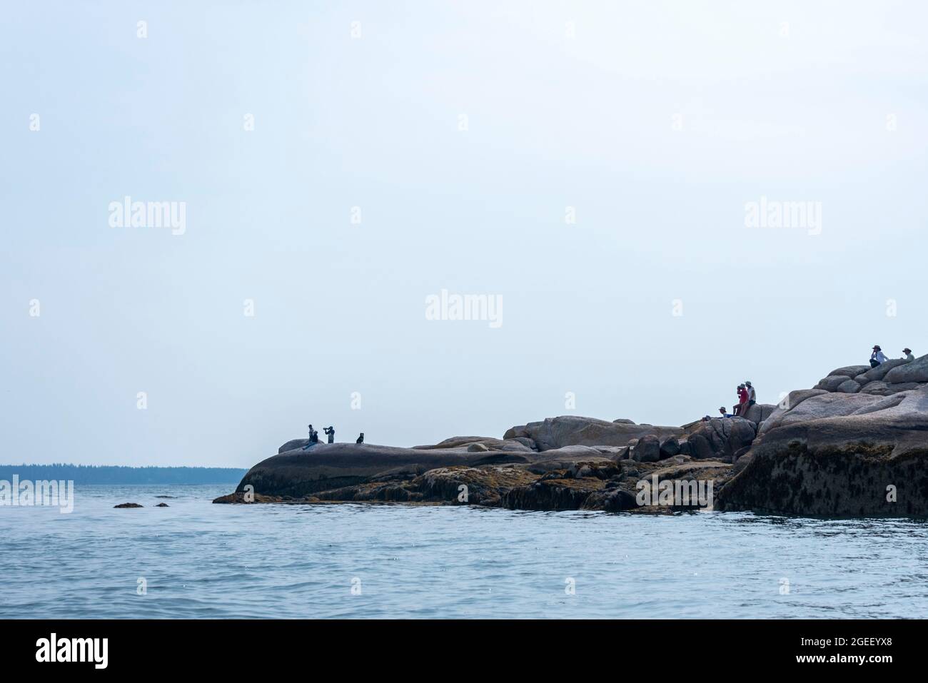 Eine Gruppe von Menschen am Water's Edge on Rocks Stockfoto