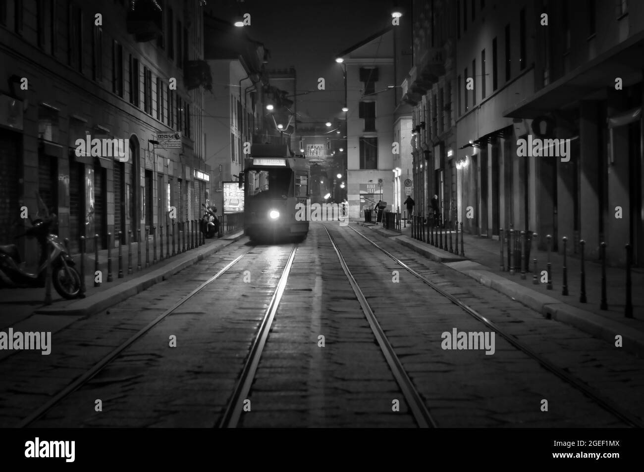 MAILAND, ITALIEN - 19. Dez 2020: Eine Graustufe einer Straßenbahn auf den Schienen bei Nacht in Mailand, Italien Stockfoto