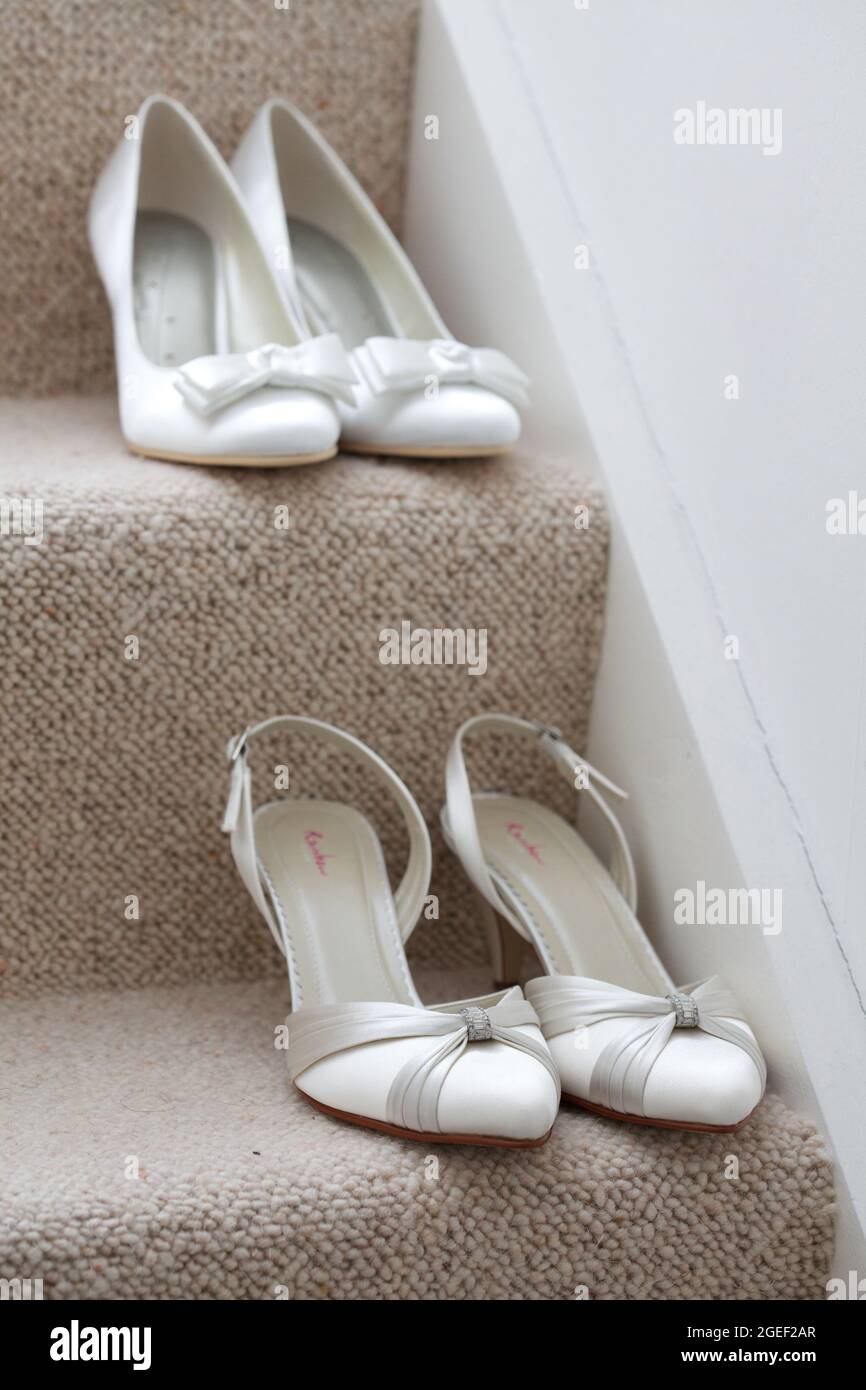 Nahaufnahme von zwei Paar weißen Schuhen mit hohem Absatz auf den Stufen eines Korridors Stockfoto