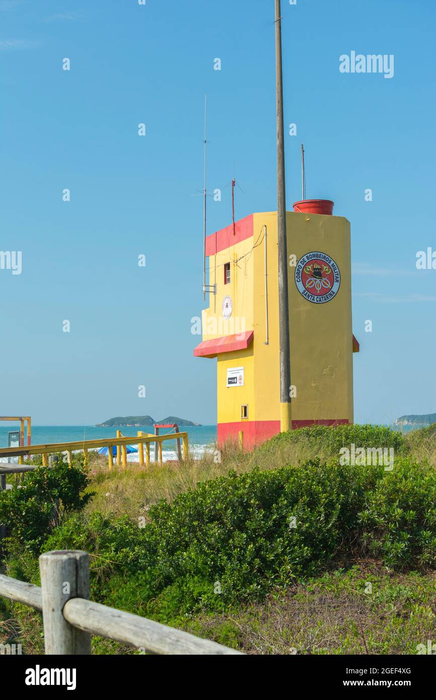 Florianopolis, Brasilien. 10. August 2019: Holzpromenade am Strand mit Rettungsschwimmerturm an einem leeren Strand mit klarem Sand und blauem Meer im Süden Stockfoto