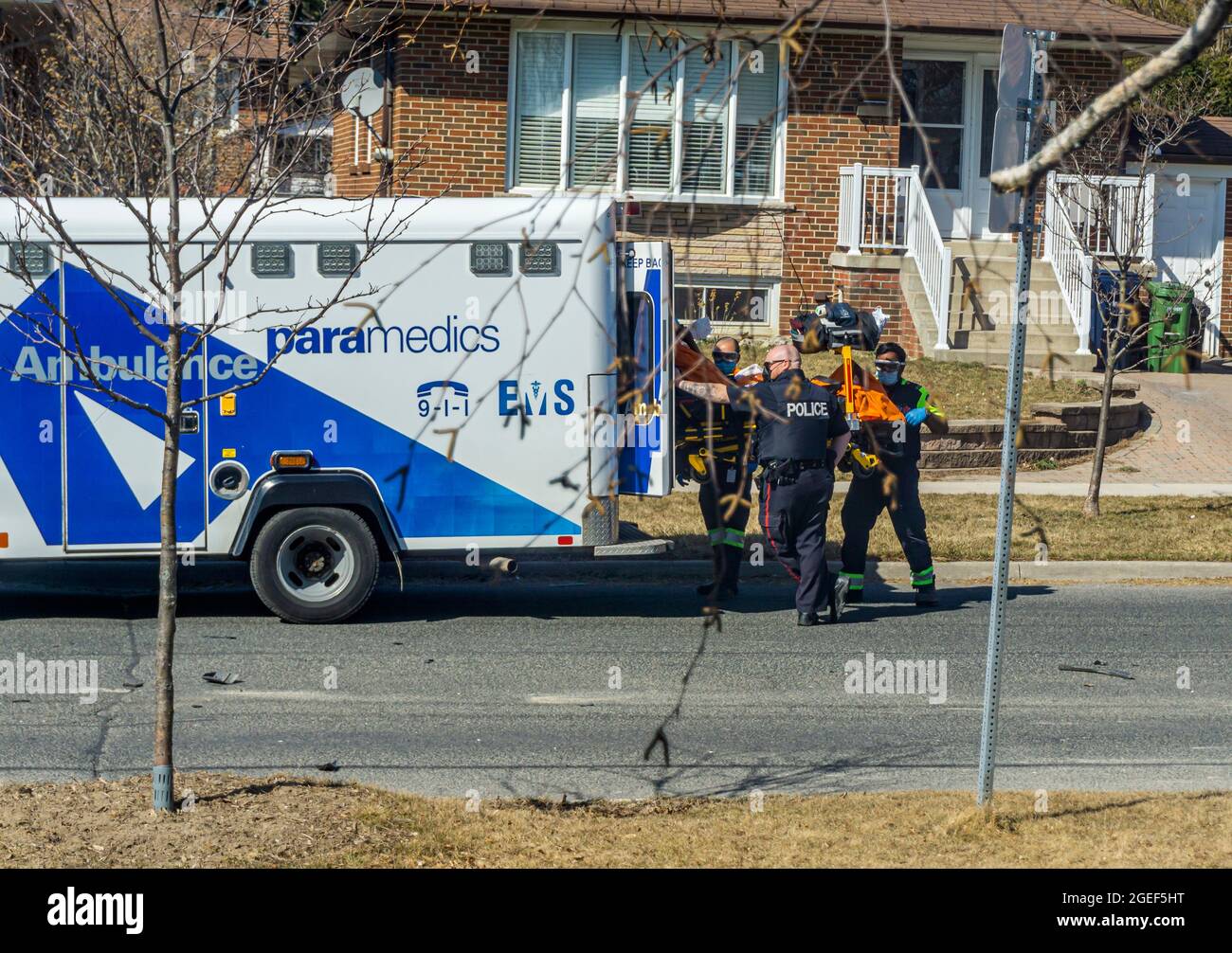 Toronto, Kanada, März 2021 - Sanitäter und Polizisten laden eine Person in einen Rettungswagen Stockfoto