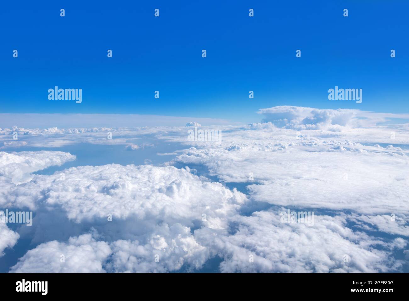 Draufsicht aus dem Flugzeugfenster auf schöne Cumulus flauschige weiße Wolken am blauen Himmel mit heller Sonne. Perfekte abstrakte Himmel Hintergrund, Tapete Stockfoto