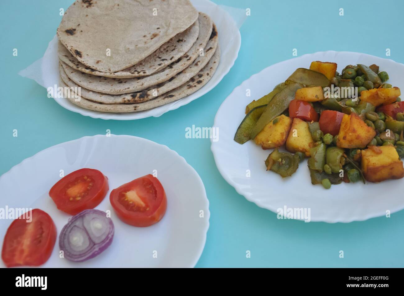 Indian Food - Matar Paneer Gemüse, Roti und Salat auf weißem Teller mit hellblauem Hintergrund Stockfoto