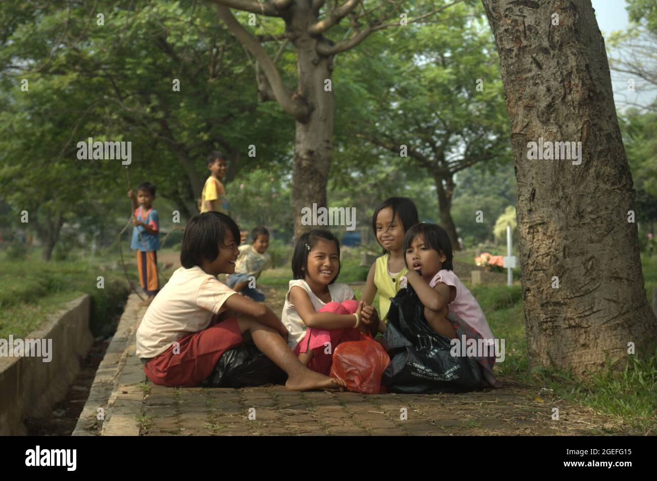 Porträt von Kindern, die auf dem öffentlichen Friedhof Pondok Kelapa in Ost-Jakarta, Indonesien, Plastikmüll sammeln. Einige von ihnen arbeiten täglich; meist durch das Angebot von Grabreinigung. Stockfoto