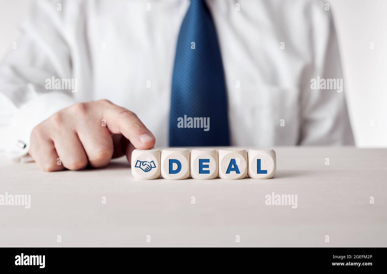 Geschäftsmann drückt mit dem Wort Deal seinen Finger auf die Holzwürfel. Geschäftskompromiss oder Vertragskonzept. Stockfoto