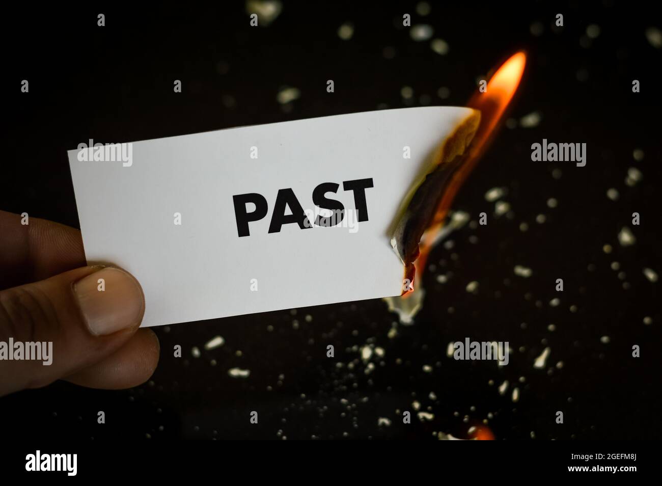 Brennende Vergangenheit, menschliche Hand hält das Wort Vergangenheit auf einem Papier geschrieben brennen mit Flamme und Asche auf schwarzem Hintergrund, Konzept Stockfoto
