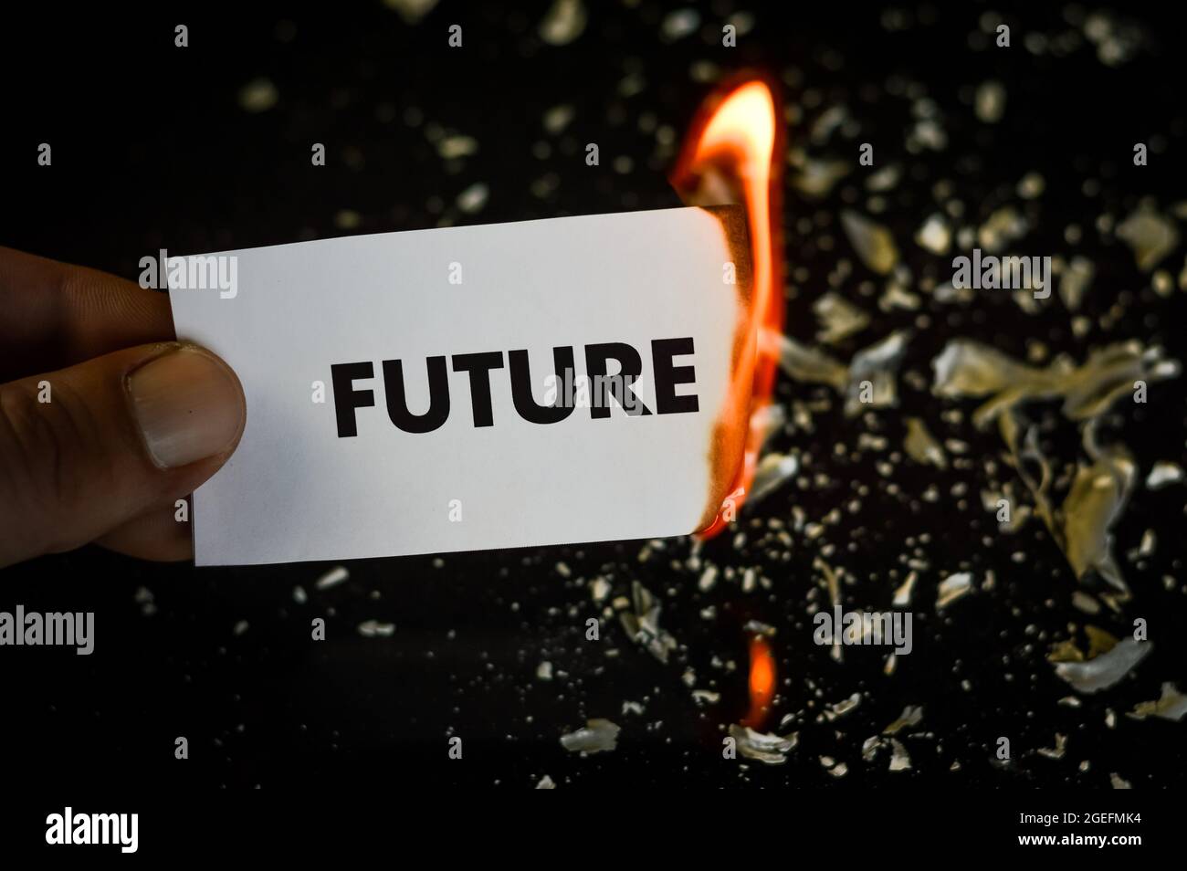 Brennende Zukunft, menschliche Hand hält das Wort Zukunft auf einem Papier geschrieben brennen mit Flamme und Asche auf einem schwarzen Hintergrund, Konzept Stockfoto