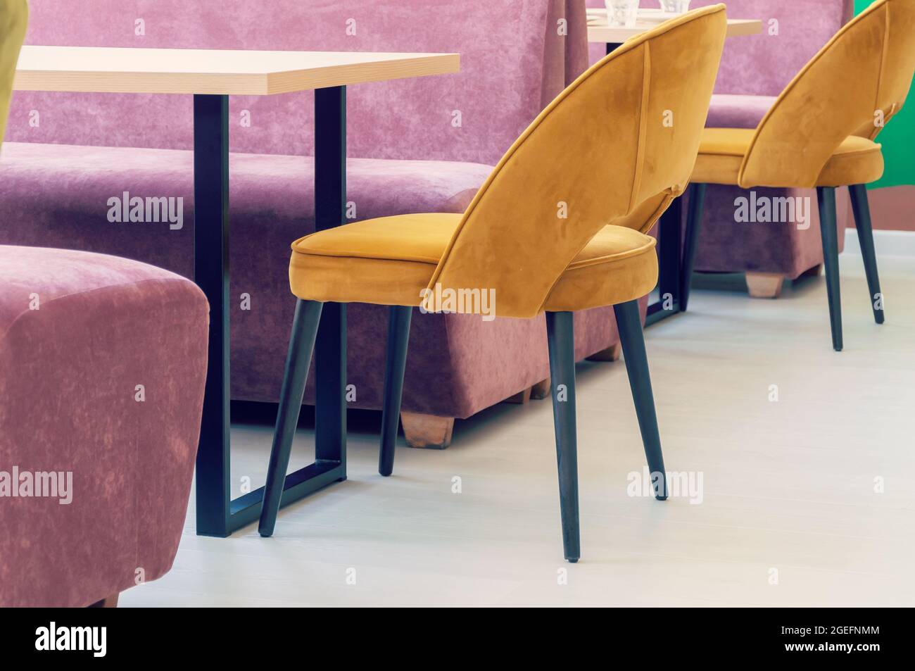 Eine Reihe von Tischen mit weichen, komfortablen violetten Stühlen für Besucher des Food Court eines modernen Einkaufszentrums Stockfoto