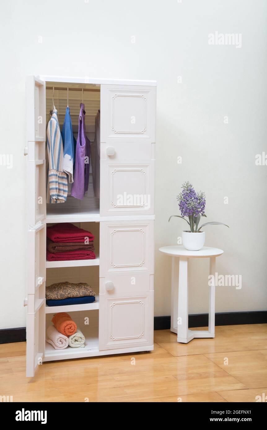 Offener Kunststoff-Kleiderschrank mit Kleidung im Schlafzimmer Hintergrund Stockfotografie