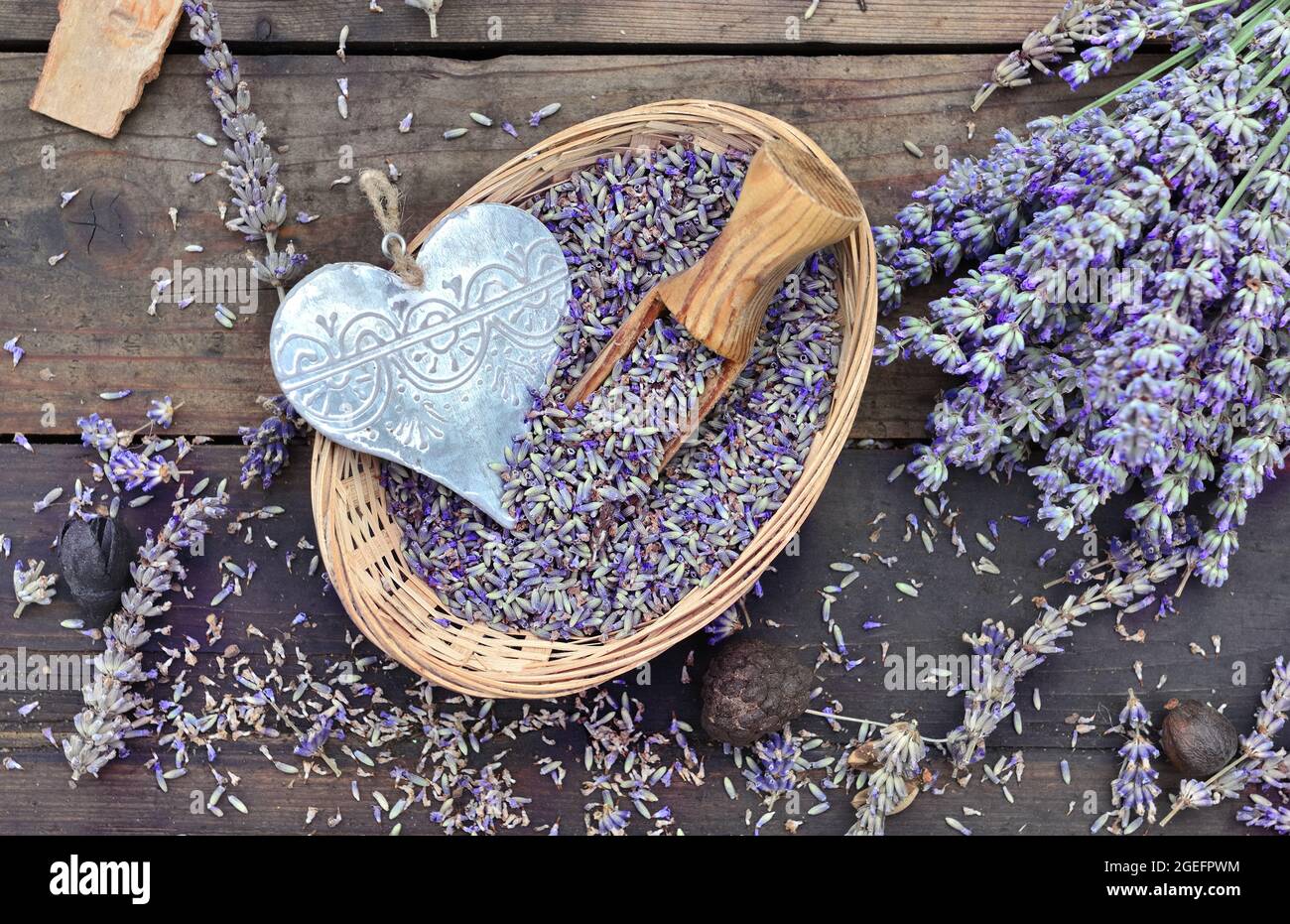 Dekoratives Herz aus Metall in einem kleinen Korb voller Lavendel auf einem Holztisch Stockfoto