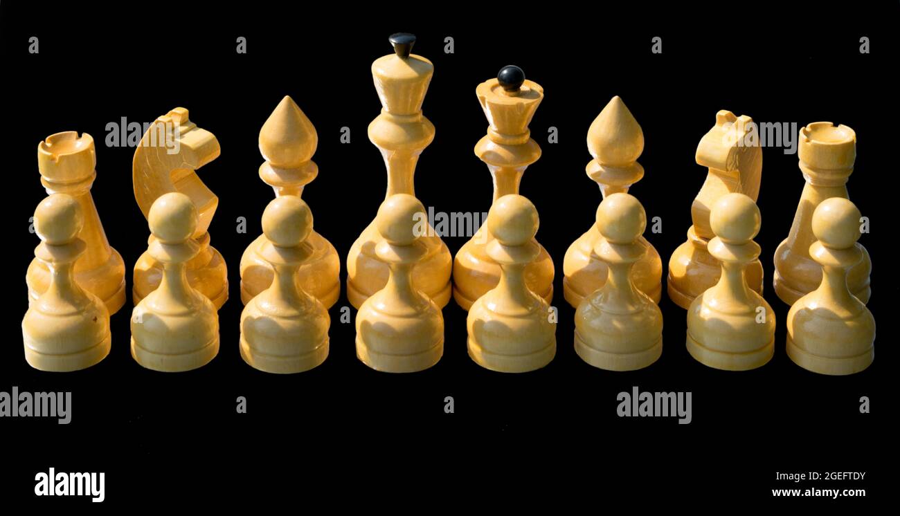 Weiße Schachfiguren aus Holz isoliert auf schwarzem Hintergrund. Stockfoto