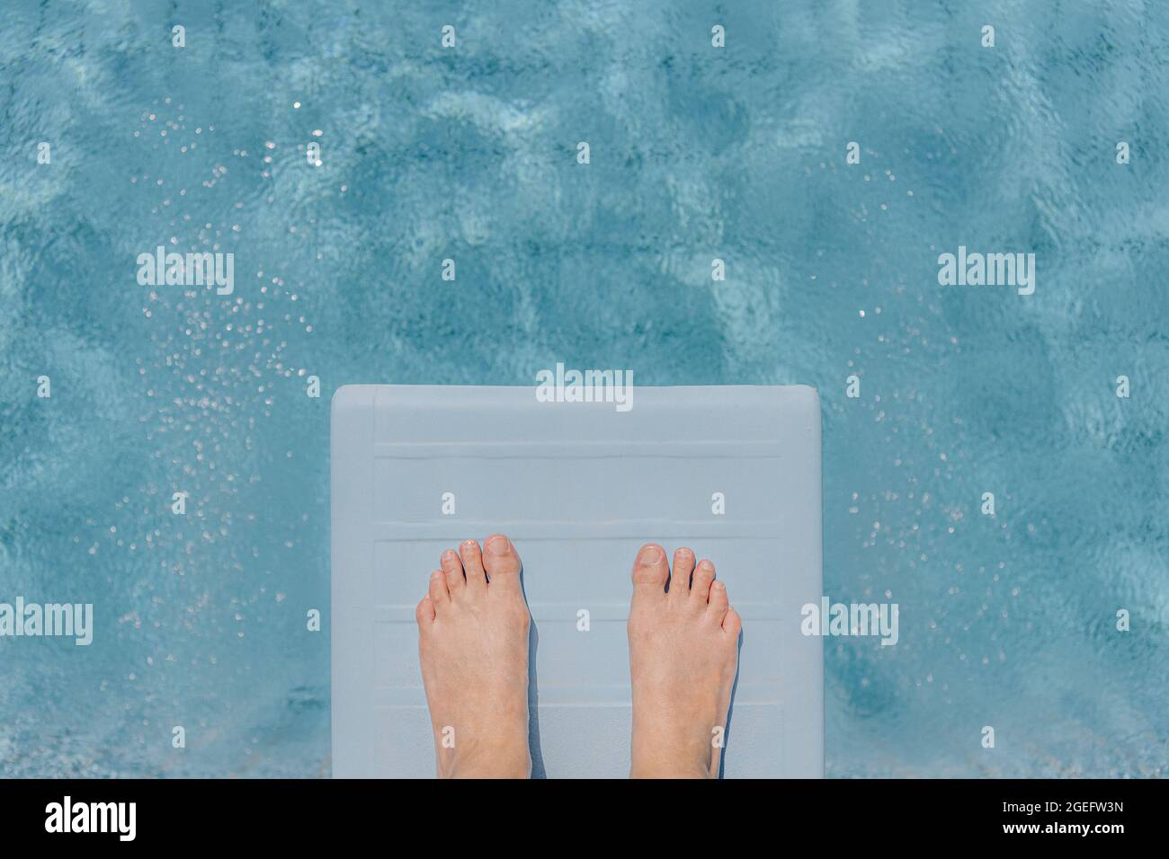 Die Füße der Frau auf einem Sprungbrett in einem privaten Pool zu Hause, während eines Aufenthalts im Sommer Stockfoto