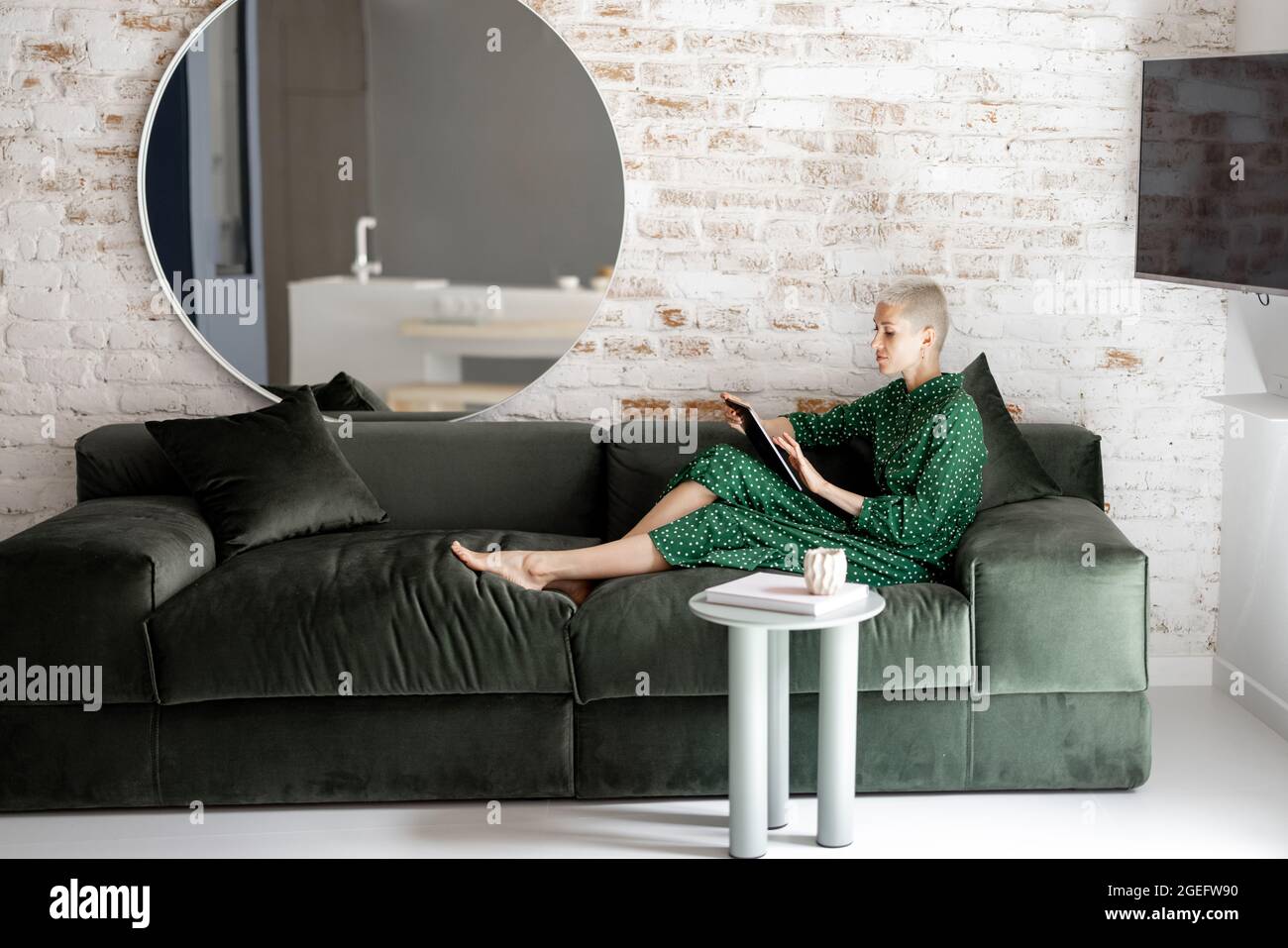 Elegante Frau mit digitalem Tablet auf der Couch zu Hause Stockfoto