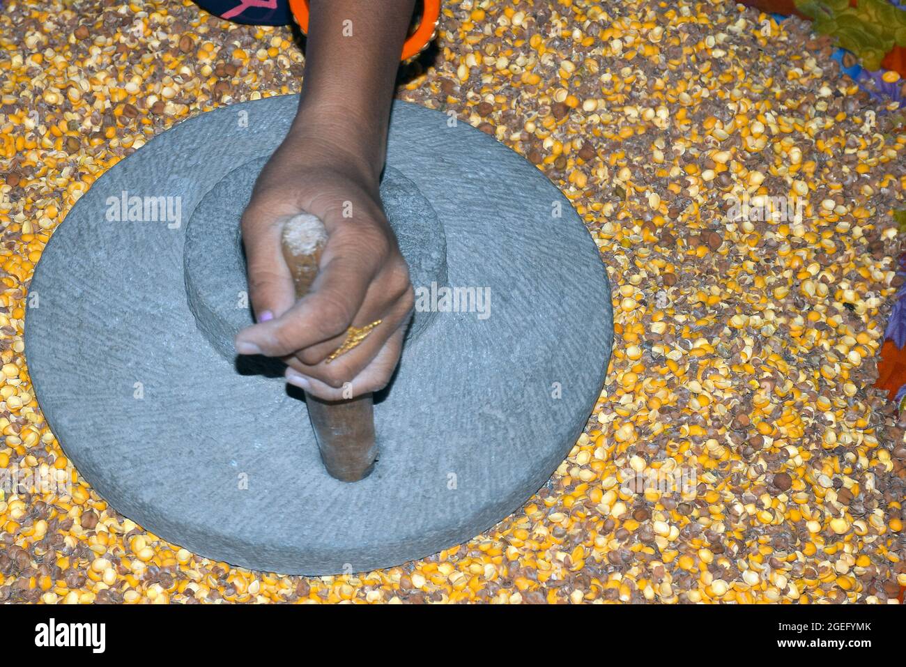 Die Hand einer Dorffrau mahlt in einer alten, handbetriebenen Mehlmühle Gramm. Stockfoto