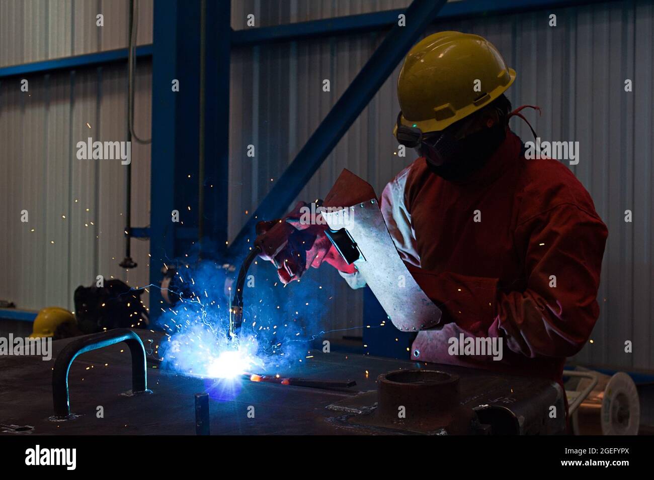 Ein Schweißer verwendet eine Lichtbogenschweißmaschine in einer Fertigungswerkstatt. Stockfoto