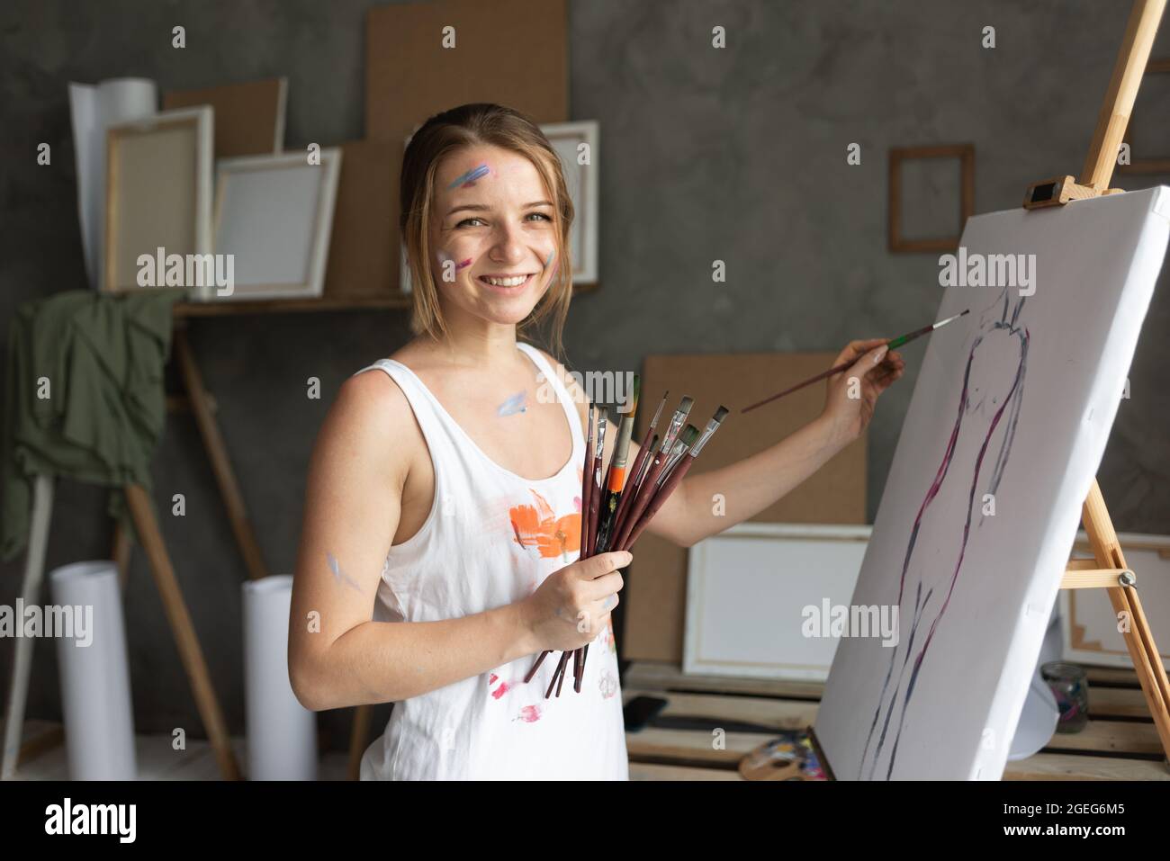 Eine Künstlerin arbeitet in einem Kunststudio in der Nähe der Leinwand und malt mit einem Pinsel. Stockfoto