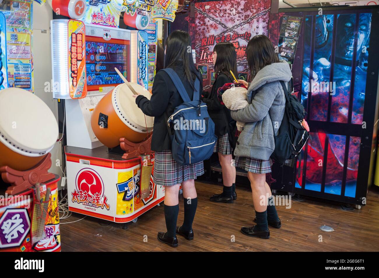 25.12.2017, Kyoto, Japan, Asien - drei japanische Schülerinnen in Schuluniform stehen vor einer Spielmaschine und spielen ein Taiko no Tatsujin. Stockfoto