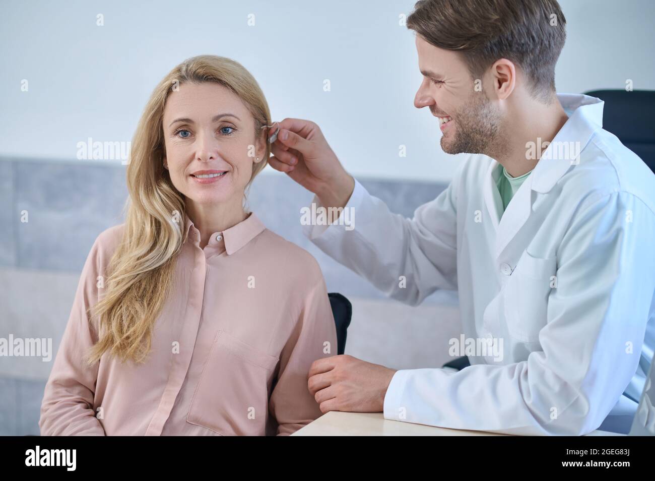 Patientin, die ihr Hörgerät von einem qualifizierten Arzt reparieren lassen muss Stockfoto