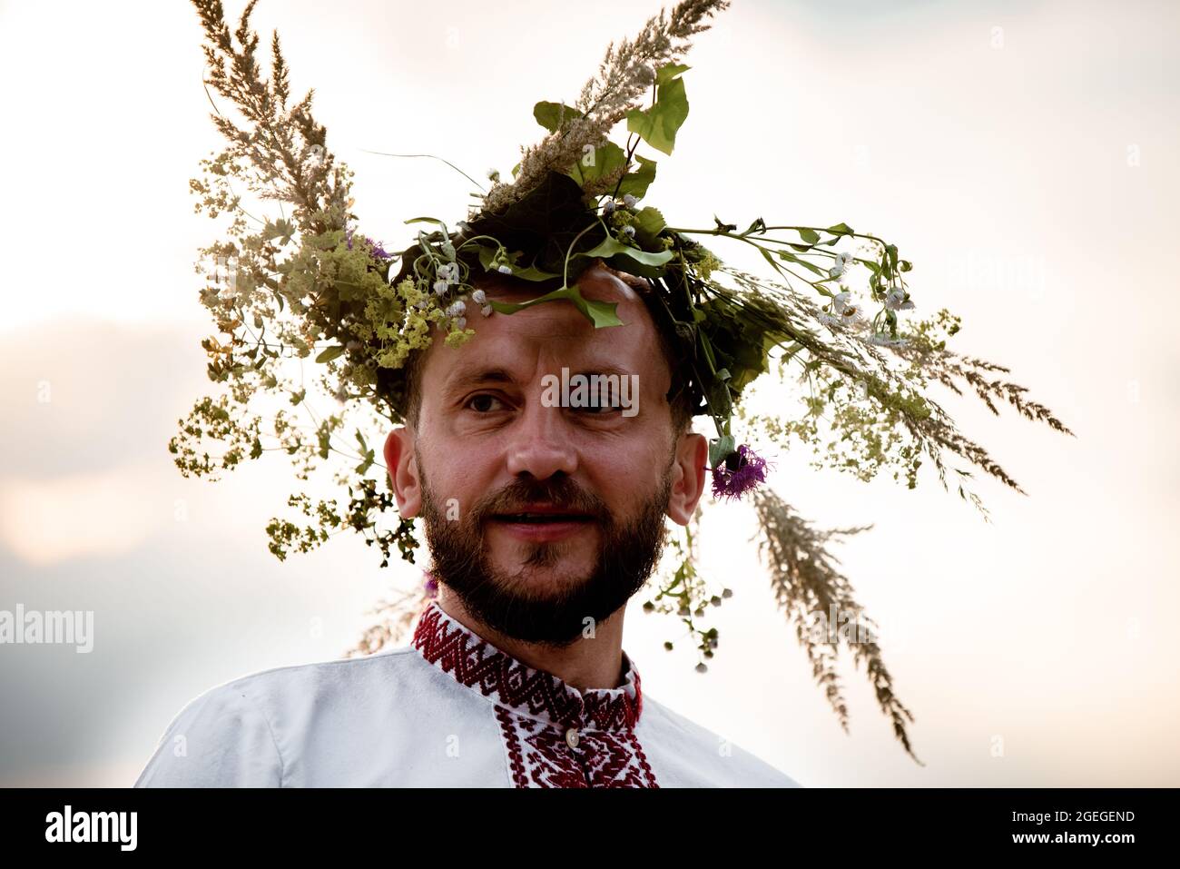 Warschau, Polen, 2021. Juni: Die Menschen feiern die Kupala-Nacht, den traditionellen slawischen Feiertag. Porträt eines Mannes mit Blumenkranz und belarussischer Fotze Stockfoto