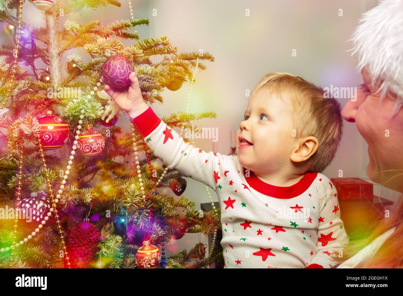 Mutter und Kleinkind Junge setzen Ball auf Weihnachtsbaum Stockfoto