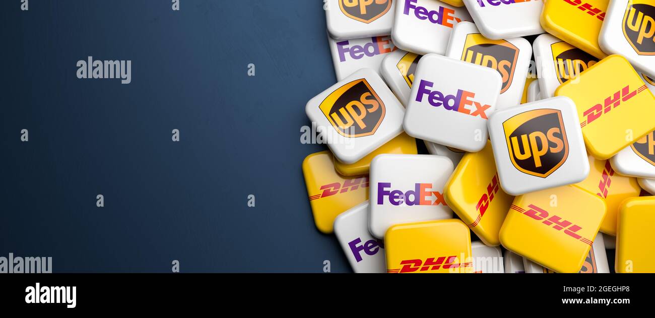 Logos der konkurrenden Versand- und Empfangsdienste FedEx, UPS United Parcel Service und DHL auf einem Haufen auf einem Tisch. Speicherplatz kopieren. Webbanner-Format. Stockfoto