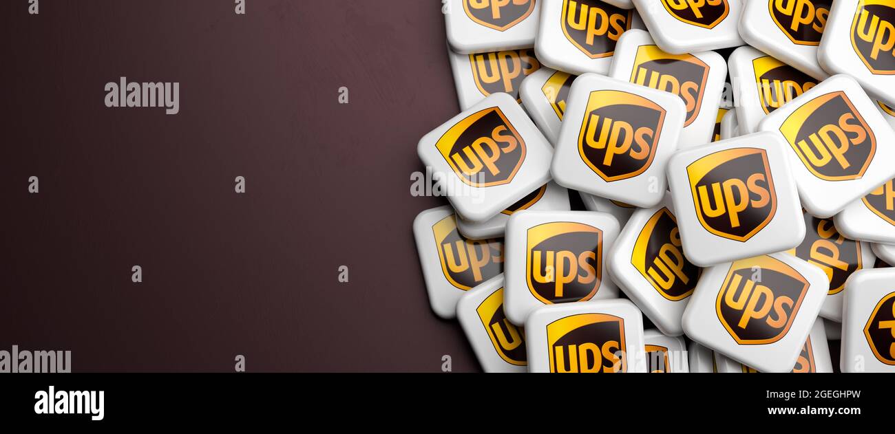 Die Logos der Versand- und Empfängerfirma UPS United Parcel Service auf einem Haufen auf einem Tisch. Speicherplatz kopieren. Webbanner-Format. Stockfoto