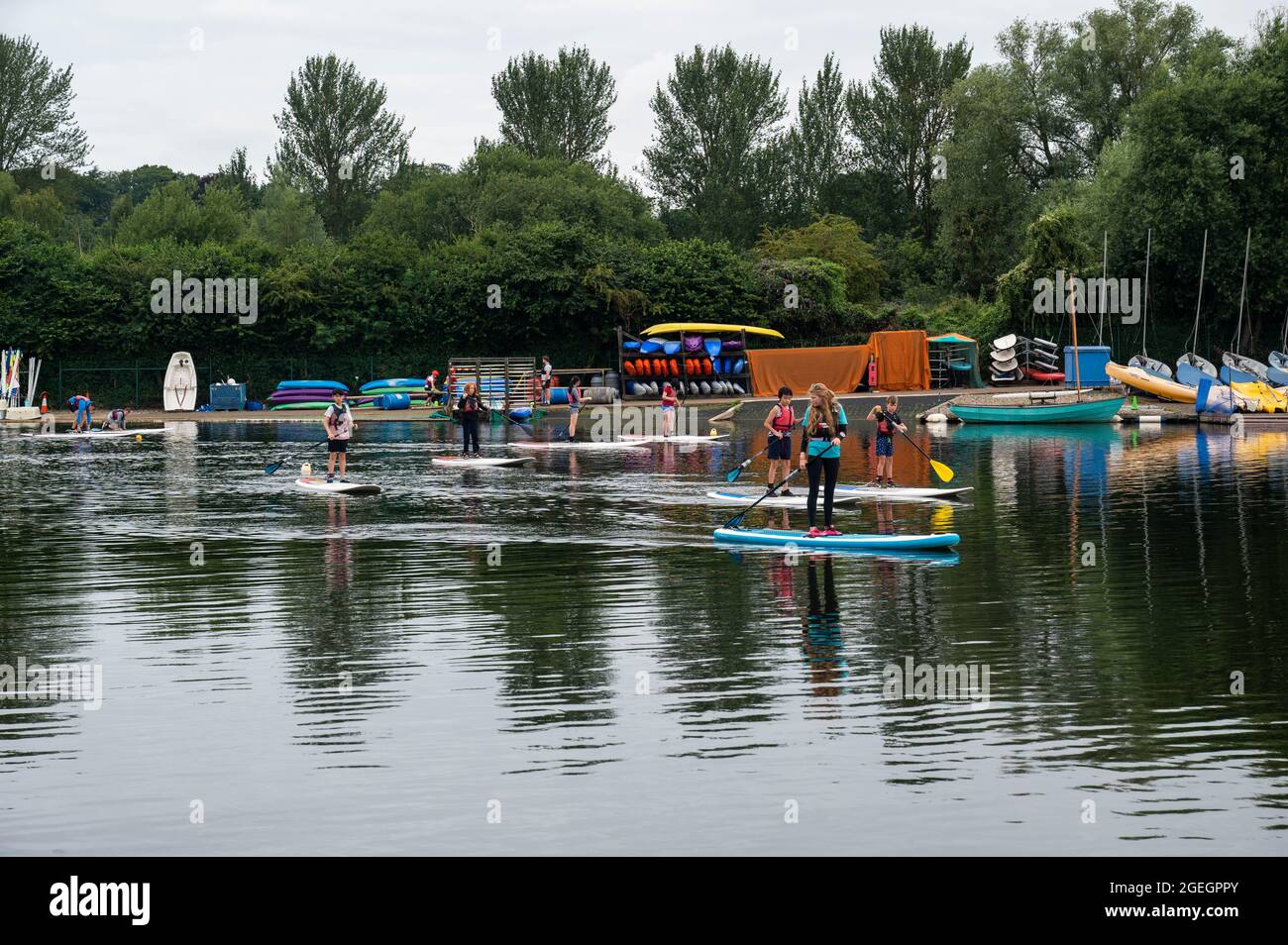 Whittligham Broad mit Kindern, die unter Anleitung das Paddleboard lernen, alle tragen Schwimmwesten Stockfoto