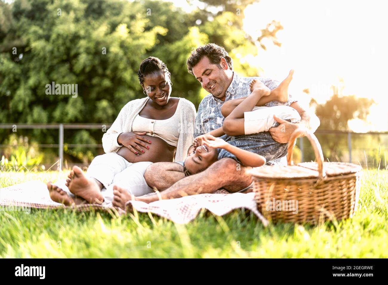 Glückliche verspielte multirassische Familie Spaß im Park machen ein Picknick zusammen - Eltern lieben Konzept Stockfoto