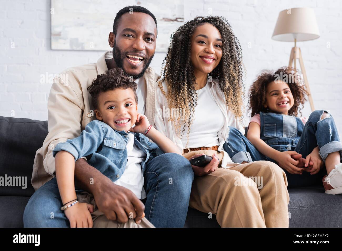 Fröhliche afroamerikanische Familie, die zu Hause Fernsehen schaut Stockfoto