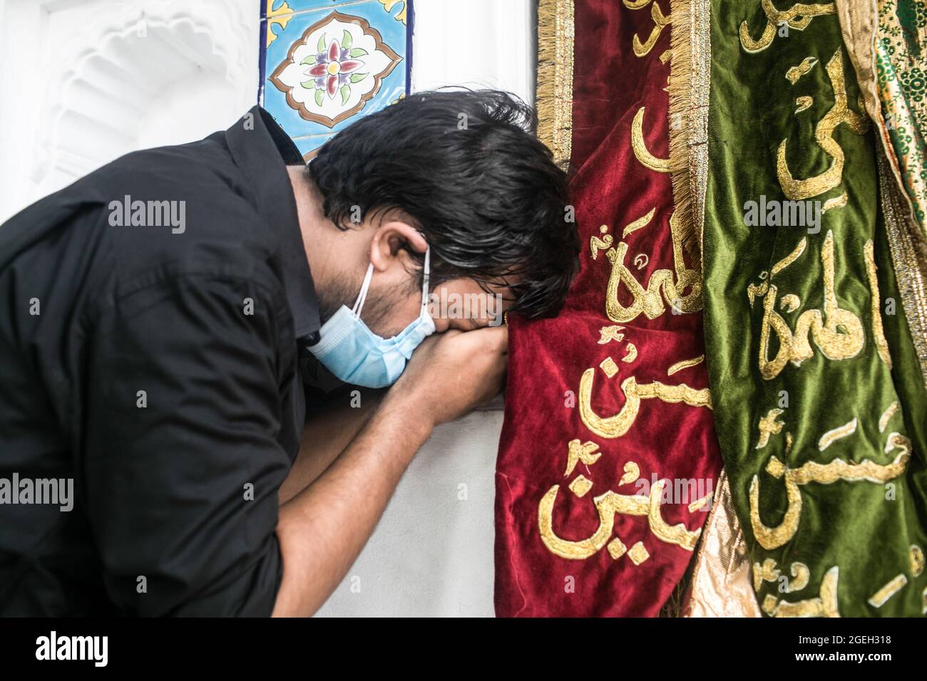 Ein schiitischer muslimischer Mann aus Bangladesch, der die Flagge mit Stickereien küsst, betet darauf.Aschura ist der zehnte Tag von Muharram, dem ersten Monat des islamischen Kalenders, der weltweit zum Gedenken an das Martyrium von Imam Hussain, dem Enkel des Propheten Muhammad, beobachtet wird. (Foto von Sazzad Hossain / SOPA Images/Sipa USA) Stockfoto
