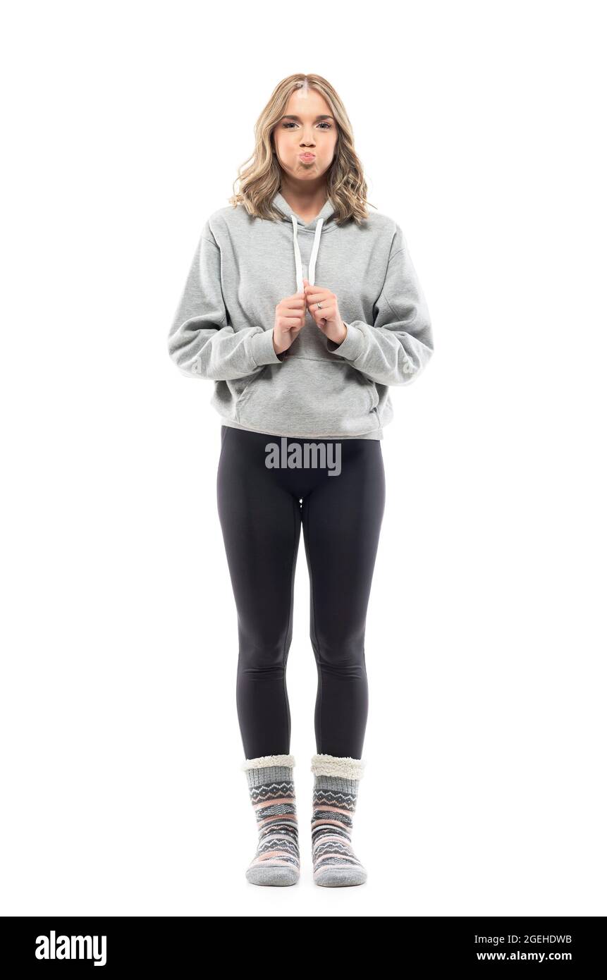 Nette lustige junge Frau, die mit geblasen geblasenen Wangen Atem hält. Ganzkörperporträt isoliert auf weißem Hintergrund Stockfoto