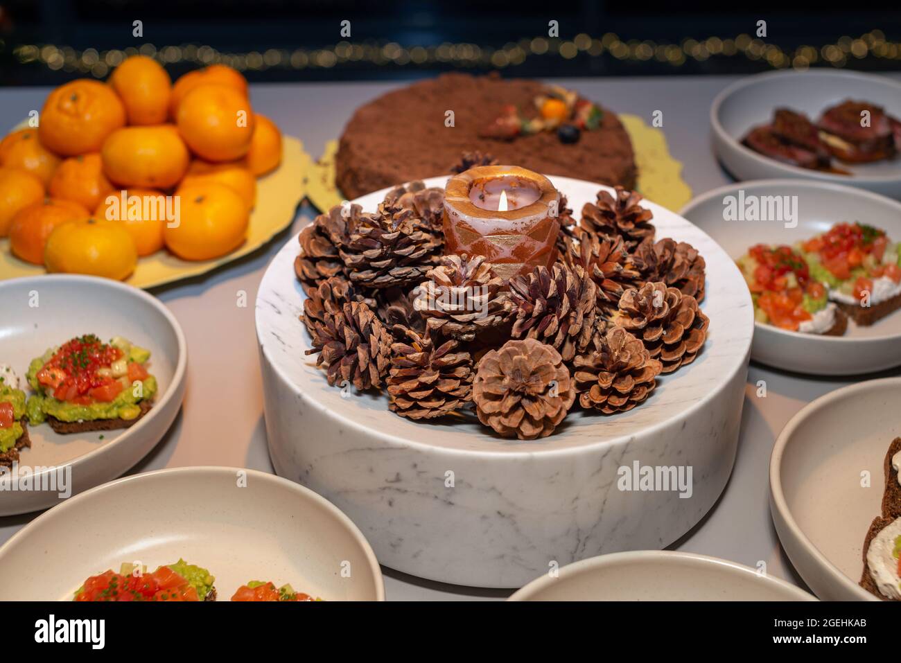 Heiligabend, dekorierter Adventskranz mit Tannenzapfen und einer Kerze. Wunderschöne Tischkulisse für das Weihnachtsessen. Selektiver Fokus. Stockfoto