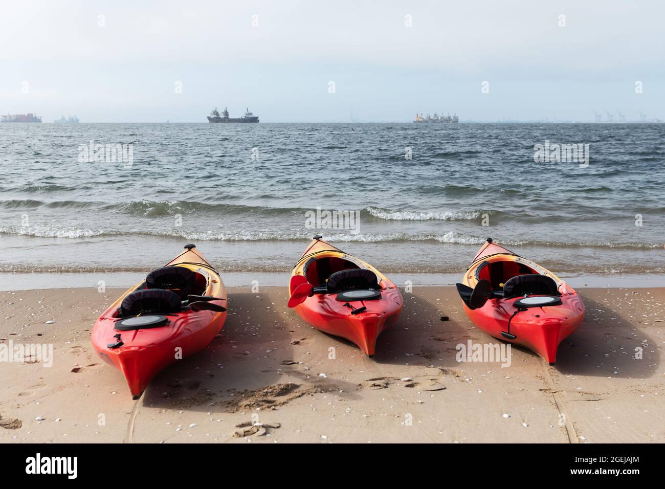 Drei rote Kajaks bereit zum Schwimmen am Meeresrand. Sonniger Tag am Atlantik in Namibia, Afrika Stockfoto