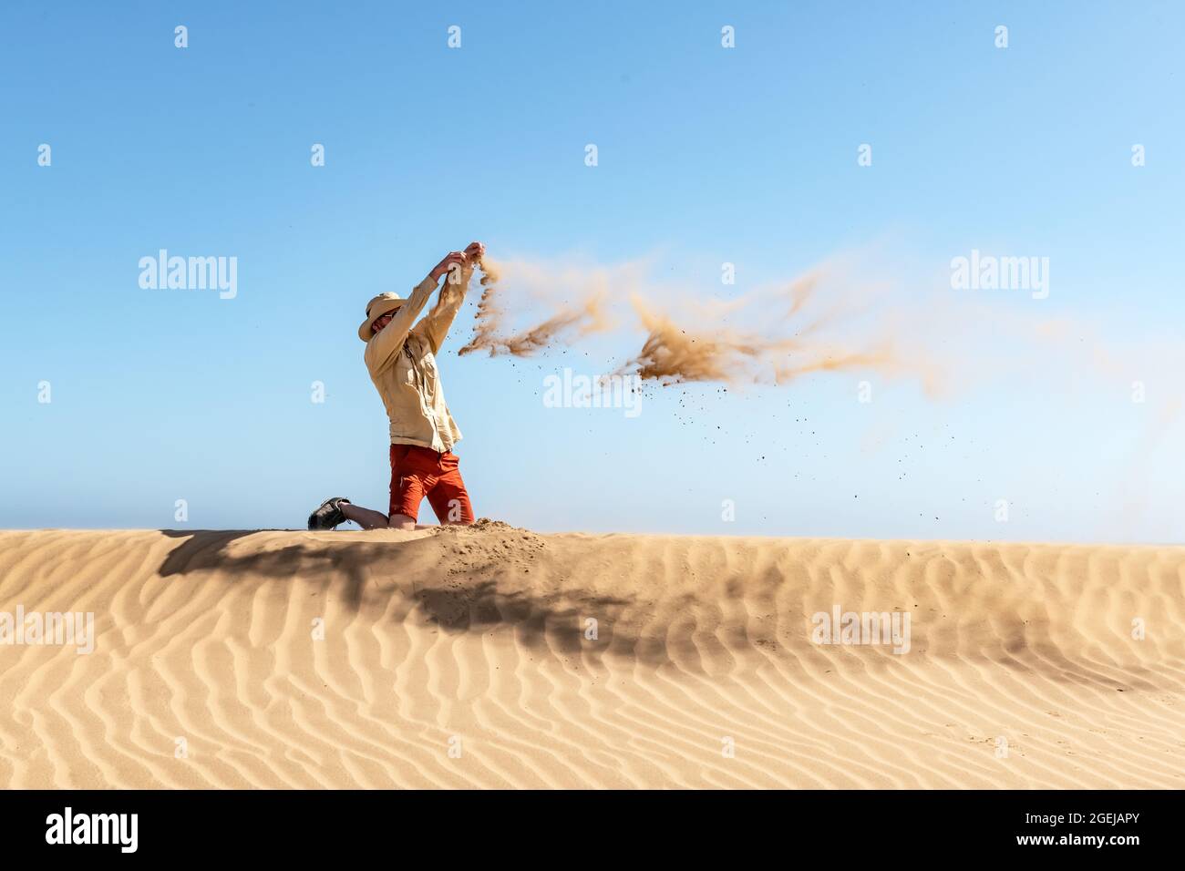 Ein einziger Mann wirft bei Sonnenaufgang Sand in die Namib-Wüste auf blauem Himmel. Reisekonzept Stockfoto