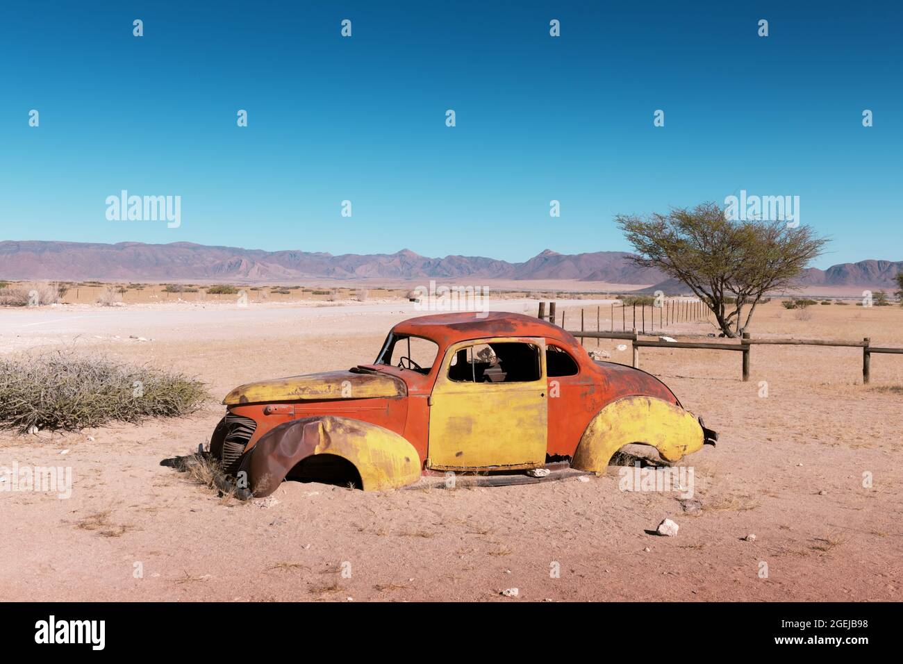 Verlassene verlassene alte Autos in der sandigen Wüste von Solitaire, Khomas Region, Namibia, mit einem blauen Himmel im Hintergrund Stockfoto